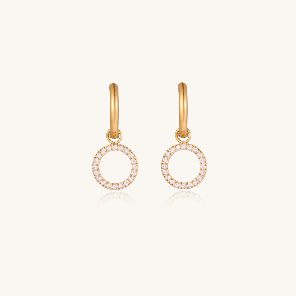 Gold-plated hoop earrings with circular cubic zirconia charm dangles displayed on neutral background.